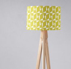 a yellow and white lamp sitting on top of a wooden tripod