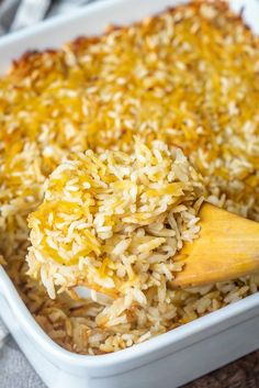 a casserole dish filled with rice and topped with a wooden spoon