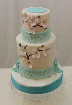 a three tiered cake decorated with flowers and ribbons