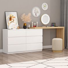 a white dresser sitting on top of a hard wood floor next to a wall with pictures above it