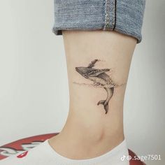 a woman's foot with a small shark tattoo on the side of her leg