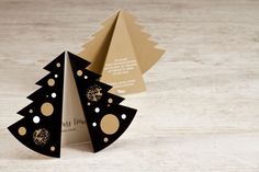 an origami christmas tree with gold dots on the bottom and black paper around it