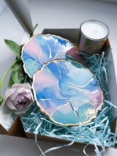 two plates in a box with some flowers and a candle next to it on the table