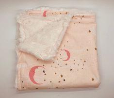 a pink blanket with stars and crescents on it is laying next to a white wall