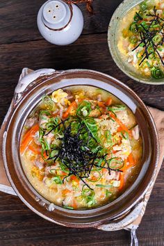 two bowls filled with soup on top of a wooden table next to an empty plate