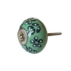 a close up of a green knob on a white surface with an intricate design and metal handle