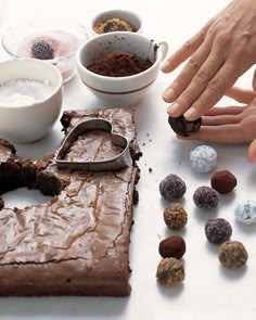 a table topped with lots of different types of desserts and hands reaching for it