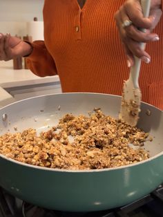 a woman in an orange shirt is stirring food into a pan