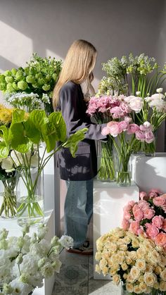 a woman is looking at flowers in vases