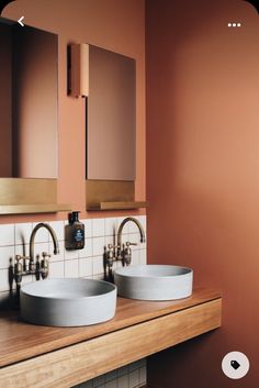 two sinks in a bathroom with orange walls