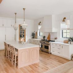 a large kitchen with white cabinets and wooden flooring, along with an island in the middle