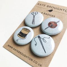 three buttons with needle, thread and knitting needles on them sitting on top of a piece of paper