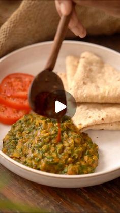 a person is pouring sauce on some tortilla bread and tomatoes in a white bowl