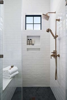 a white tiled bathroom with shower and window