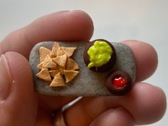 a person holding a tiny rock with food on it