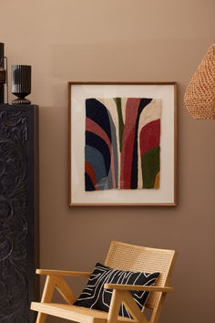 a wooden chair sitting in front of a painting on the wall next to a lamp