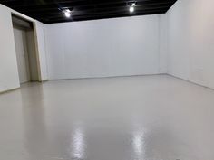 an empty room with white walls and flooring is pictured in this image, there are lights on either side of the door