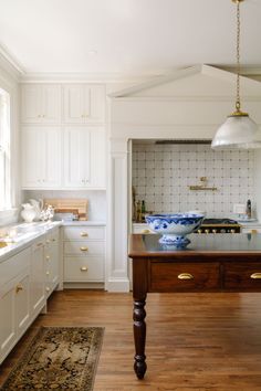 a large kitchen with white cabinets and wooden flooring, along with an island in the middle