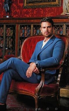 a man in a blue suit sitting on a red chair