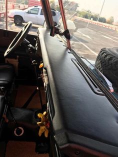 the interior of an old truck with its door open and flowers growing on the dashboard