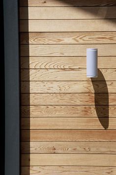 a wall mounted light on the side of a wooden building with wood slats in the background