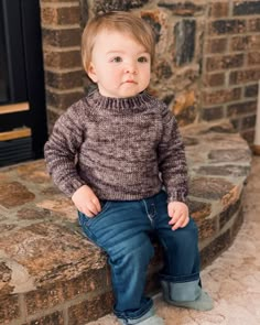 a little boy sitting on top of a stone step next to a fire place with his hands in his pockets