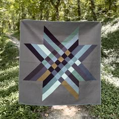 a patchwork quilt hanging in the woods