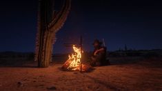 a man sitting next to a fire in the desert