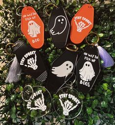 six key chains with different designs on them sitting in front of some plants and leaves