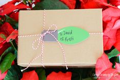 a gift wrapped in brown paper and tied with twine, surrounded by red flowers