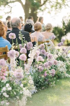 an outdoor ceremony with flowers and people sitting in chairs