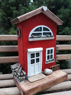 a small red house sitting on top of a wooden bench