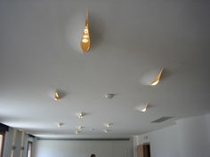 a man standing in an empty room with lights on the ceiling and windows above him