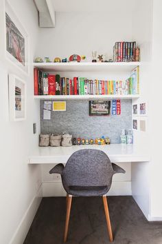 a chair sitting in front of a white desk with books on the shelves above it