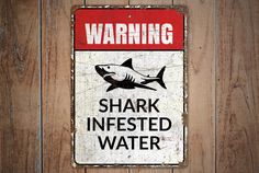 a warning sign on the side of a wooden wall that says, shark infested water