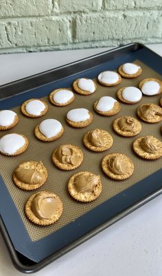 cookies with peanut butter and marshmallows on a cookie sheet in front of a brick wall