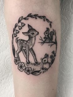 a tattoo on the leg of a woman with an image of a deer and squirrel