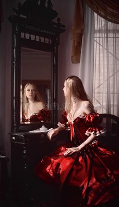 a woman in a red dress is looking at herself in the mirror royalty images and stock photography