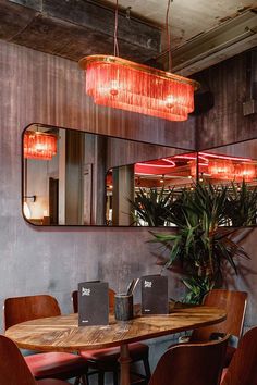 a wooden table surrounded by brown chairs and red lights hanging from the ceiling above it