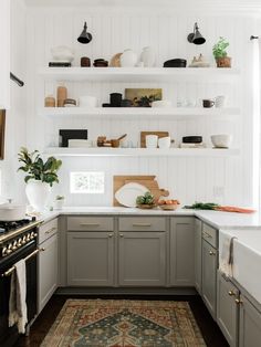 a kitchen with gray cabinets and white walls, an area rug on the wooden floor