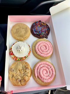 a pink box filled with lots of different flavored cookies and doughnuts on top of each other