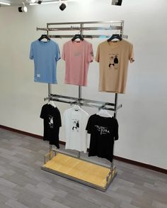 three t - shirts are hanging on a metal rack