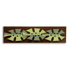 a wooden wall hanging with three green flowers on it's sides and black dots in the center