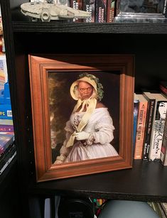 a portrait of a woman in a white dress and bonnet sits on a bookshelf