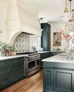 a large kitchen with green cabinets and white counter tops, along with an island in the middle