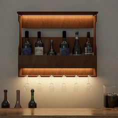 a wooden shelf with bottles and glasses on it next to a wine glass holder that is lit up