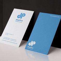 two business cards sitting next to each other on top of a white table with black background