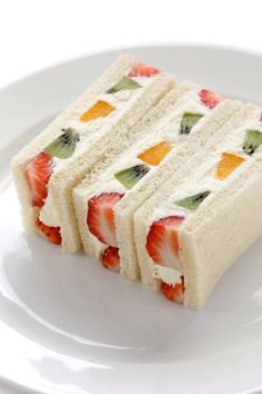 two slices of cake on a plate with strawberries and kiwis in the middle