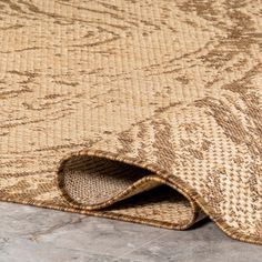 an area rug with a brown and beige pattern on the bottom, in front of a stone floor