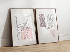 two framed art pieces sitting on top of a hard wood floor next to each other